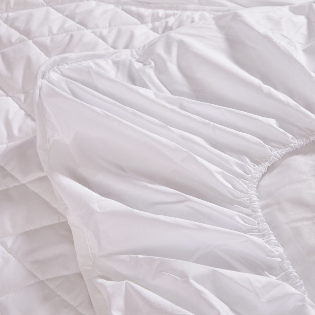 Close-up of white quilted bedding with visible stitching