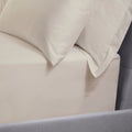Close-up of cream bedding with pillows on a bed.