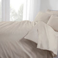 Beige bedding set on a bed with white curtains in the background