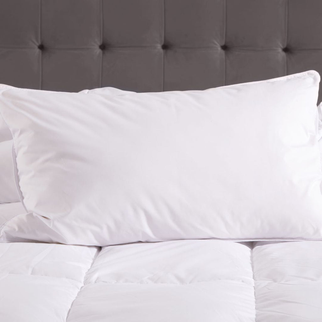 White pillows on a bed with a gray tufted headboard