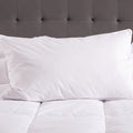 White pillows on a bed with a gray tufted headboard