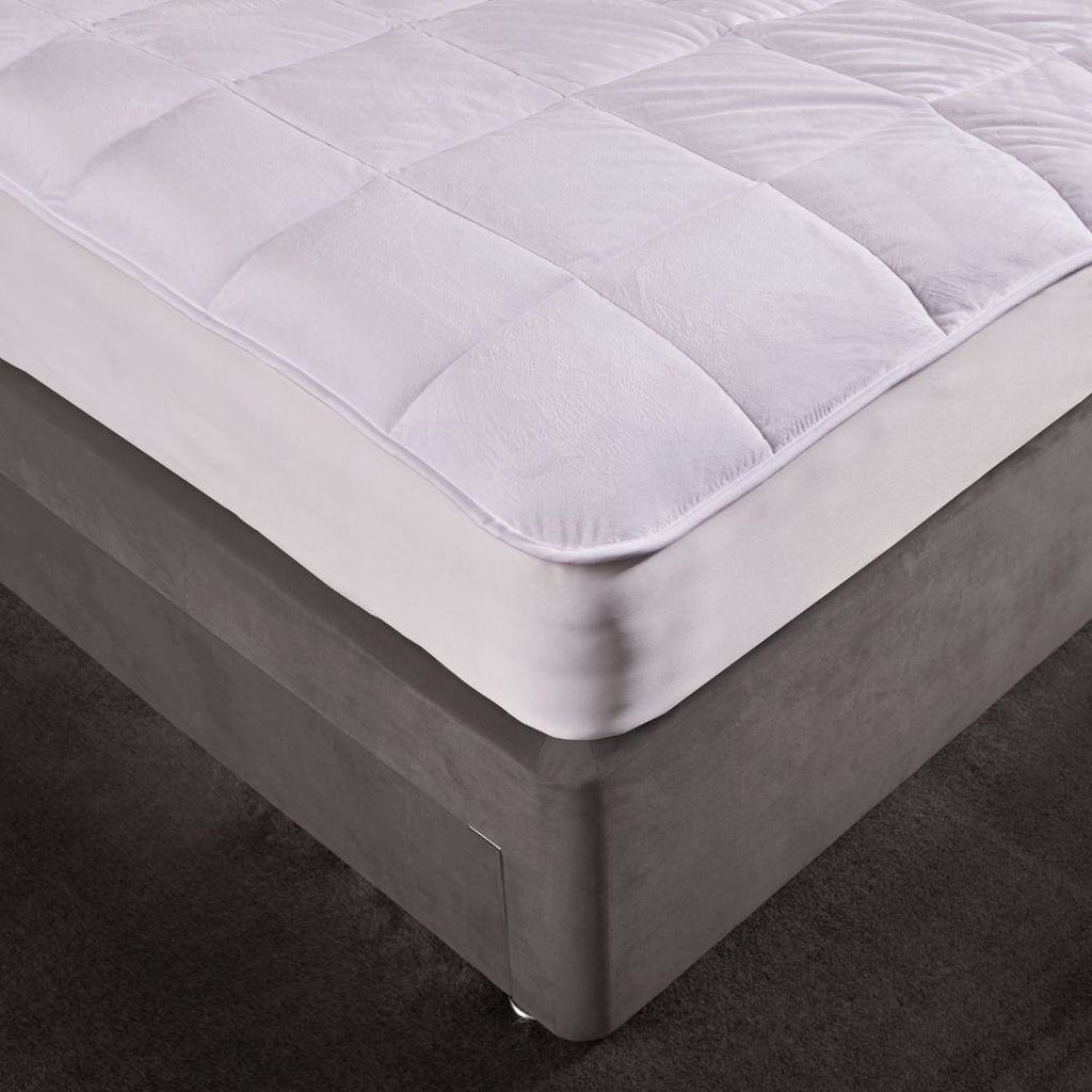 Mattress pad on a bed with a dark background