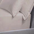 Close-up of light gray bedding with pillows on a bed.