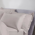 Gray satin pillowcases on a bed with a neutral background