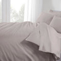 Gray bedding set on a bed with white curtains in the background