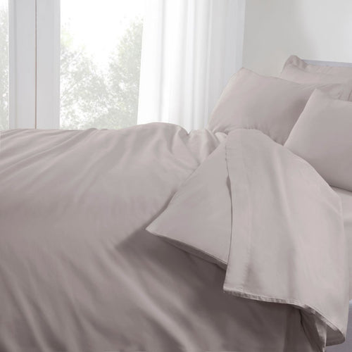 Gray bedding set on a bed with white curtains in the background