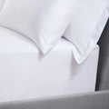 Close-up of white pillows on a bed with a gray headboard.