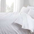 White bedding set on a bed with light streaming through the window