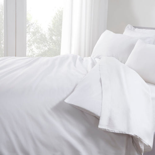 White bedding set on a bed with light streaming through the window